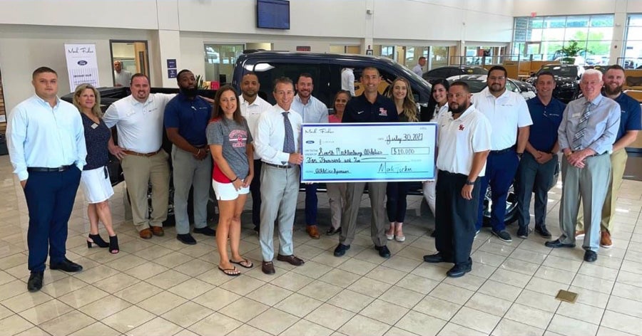Mark Ficken Ford Lincoln employees holding a check for a charitbale donation.